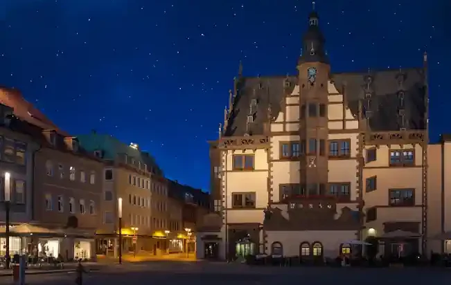 Historisches Rathaus in Schweinfurt am Abend in einem städtischen Platz, beleuchtet von Straßenlaternen.